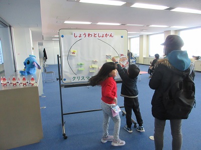 プレゼントのイラストをサンタさんのプレゼント袋に入れる子どもたち
